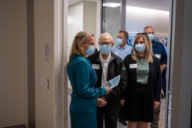 A group of five people wearing masks stand at the entrance to a room.