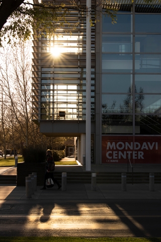 Exterior of the Mondavi Center for Performing Arts showcasing tall-paned glass windows and a lens flare.